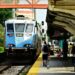 Blue train approaches a bustling station, capturing daily commute life.